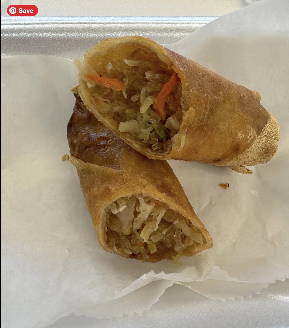 A MEGA Eggroll pulled open to show the savory filling, served with dipping sauce